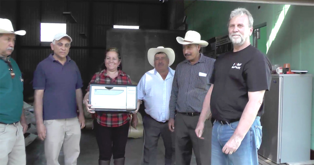 Joe Behm standing next to Guatemalan coffee farmers receiving donated Behmor Coffee Roasters
